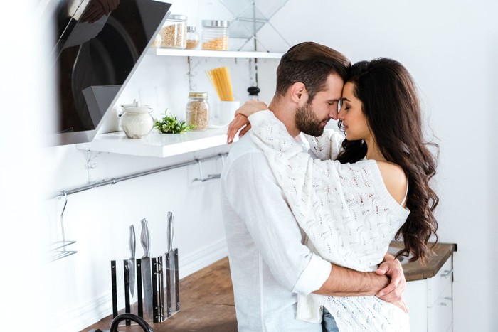 1162327901 lovely gently couple embracing with closed eyes at kitchen