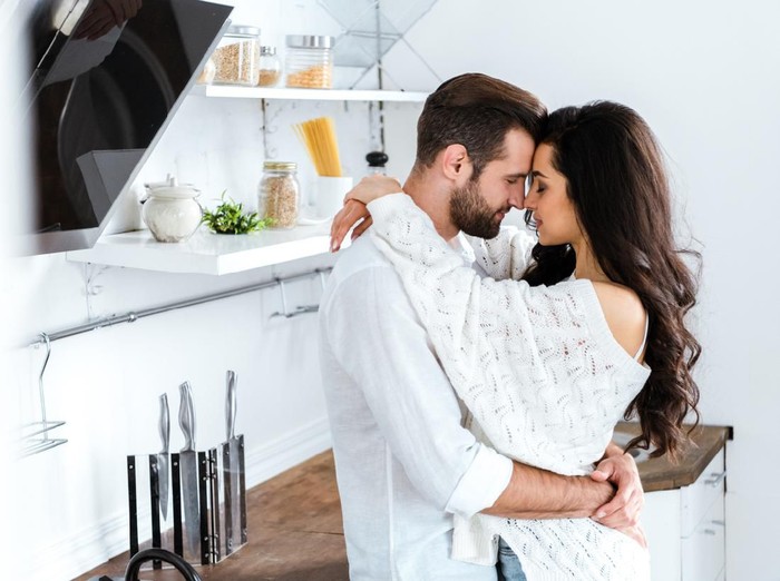 1162327901 lovely gently couple embracing with closed eyes at kitchen
