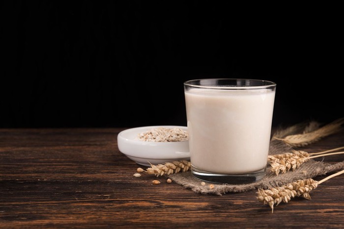 A glass of oat milk and cereal oatmeal on a wooden table. Vegetarian diet concept.