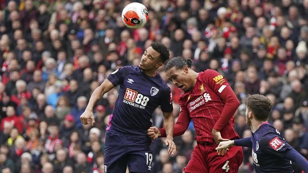 Bournemouth's Junior Stanislas, left, jumps for the ball with Liverpool's Virgil van Dijk, center, during the English Premier League soccer match between Liverpool and Bournemouth at Anfield stadium in Liverpool, England, Saturday, March 7, 2020. (AP Photo/Jon Super)