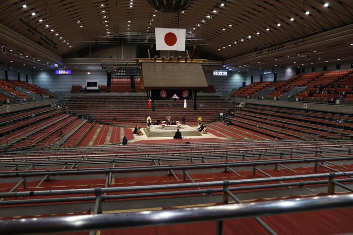 Sumo wrestlers fight on the ring as spectators' seats are empty during the Spring Grand Sumo Tournament in Osaka, western Japan, Sunday, March 8, 2020. The 15-day sumo tournament started on Sunday with no spectators, affected by fears of the new coronavirus outbreak. (Kyodo News via AP)