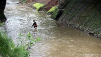 Terlihat seorang petugas  mengais sampah di kali. Rengga Sancaya