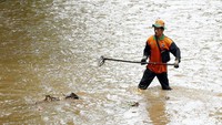 Seorang petugas membersihkan sampah di kali dengan menggunakan cangkul sampah. Rengga Sancaya