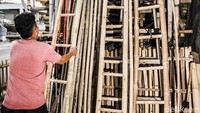 Seorang pekerja sedang menyusun tangga hasil kerajinan dari bambu. Imam Kurniawan