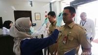 Para pegawai menjalani pemeriksaan suhu tuhuh di lobi gedung Kemenko PMK.