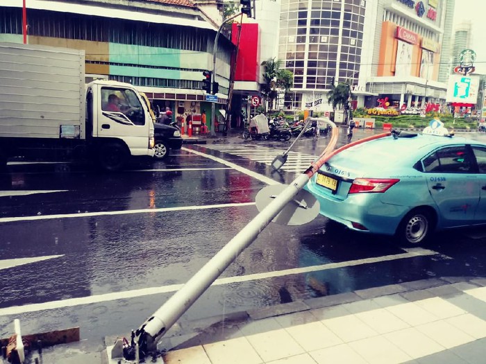 Hujan deras disertai angin kencang menyebabkan lampu Penerangan Jalan Umum (PJU) ambruk di Jalan Blauran, Surabaya. PJU ini menimpa mobil taksi yang sedang melintas.