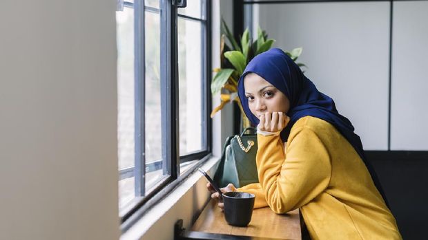 hijab Young woman sitting at sidewalk cafe and using Laptop