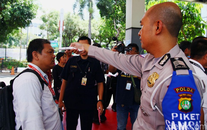 Polisi Cek Suhu Tubuh Pengunjung Samsat Polda Metro Seorang petugas dari kepolisian Polda Metro Jaya melakukan pemeriksaan pengunjung yang akan ke loket pelayanan publik, Samsat Jakarta Selatan dan Sentra Pelayanan Kepolisian Terpadu (SPKT) di Polda Metro Jaya, Jakarta Selatan, Selasa (10/3/2020). Pemeriksaan tersebut untuk mencegah penyebaran virus Corona.