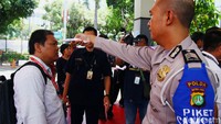 Polisi memeriksa suhu tubuh pengunjung di pintu masuk kantor SPKT dan Samsat Polda Metro Jaya, Jakarta Selatan.
