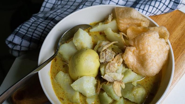 nasi kuning. indonesian yellow rice served with fried chicken on banana leaf