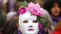 Seorang peserta aksi di peringatan Hari Perempuan Internasional mengenakan topeng saat ikut serta dalam aksi yang digelar di Kota Madrid, Spanyol, pada Minggu (8/3) lalu. AP Photo/Paul White.