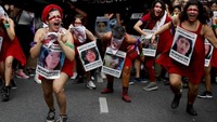 Sejumlah peserta aksi Hari Perempuan Internasional di Argentina berlari dengan mengalungi foto-foto para wanita yang hingga kini masih dikabarkan hilang. AP Photo/Natacha Pisarenko.