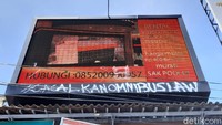 Selain melakukan pelemparan batu, iklan videotron yang berada di atas pos polisi juga tak luput dari aksi vandalisme dengan tulisan #gagalkanomnibuslaw.