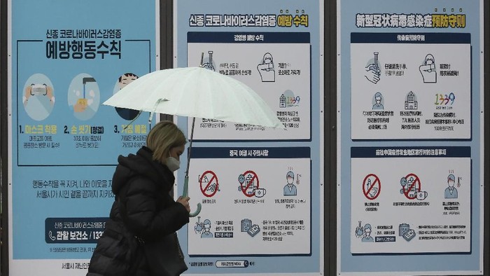 A woman wearing a face mask passes by posters about precautions against the COVID-19 illness on a street in Seoul, South Korea, Tuesday, March 10, 2020. For most people, the new coronavirus causes only mild or moderate symptoms, such as fever and cough. For some, especially older adults and people with existing health problems, it can cause more severe illness, including pneumonia. The sign reads 