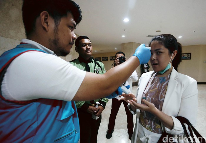 Tina Toon bersama anggota DPRD DKI Jakarta lainnya dicek suhu tubuhnya sebelum rapat paripurna, Rabu (11/3/2020). Pemeriksaan suhu tubuh anggota DPR DKI Jakarta itu menggunakan thermal gun.