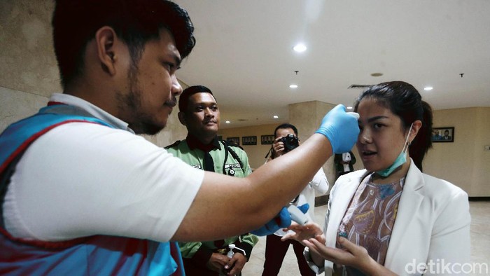 Tina Toon bersama anggota DPRD DKI Jakarta lainnya dicek suhu tubuhnya sebelum rapat paripurna, Rabu (11/3/2020). Pemeriksaan suhu tubuh anggota DPR DKI Jakarta itu menggunakan thermal gun.