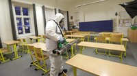 Petugas mengenakan pakaian pelindung serta masker saat menyemprotkan desinfektan di ruang-ruang kelas salah satu sekolah yang berada di Kota Praha, Republik Ceko.