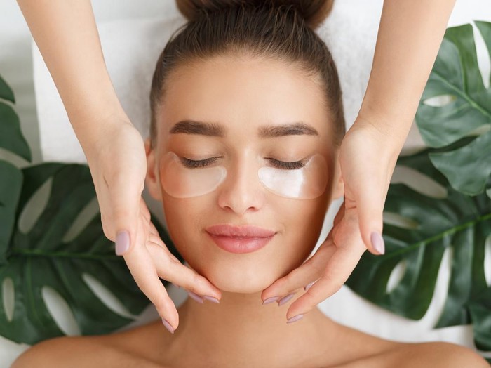 skincare Young woman with eyes closed applying face cream.