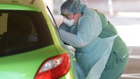 Saat melakukan tes corona via drive through, pengendara tinggal menurunkan kaca mobil. Petugas berpakaian lengkap akan mendatangi dan mengambil sampel dari saluran pernapasan dan tenggorokan. (Getty Images/Tracey Nearmy)