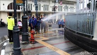 Pagar di sepanjang trotoar juga disemprot dengan air.