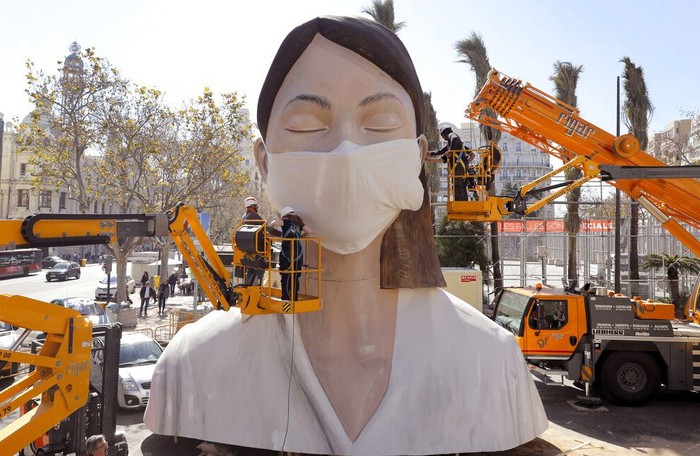 Sejumlah pekerja memasang masker di salah satu patung raksasa yang akan ditampilkan di festival Las Fallas, Valencia, Spanyol, Rabu (11/3/2020) waktu setempat.