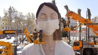 Sejumlah pekerja memasang masker di salah satu patung raksasa yang akan ditampilkan di festival Las Fallas, Valencia, Spanyol, Rabu (11/3/2020) waktu setempat.