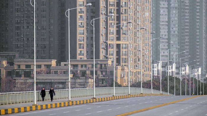 FILE - In this  Jan. 28, 2020, file photo, people wearing face masks walk down a deserted street in Wuhan in central Chinas Hubei Province. As the coronavirus spreads around the world, International health authorities are hoping countries can learn a few lessons from China, namely, that quarantines can be effective and acting fast is crucial. On the other hand, the question before the world is to what extent it can and wants to replicate China’s draconian methods. (AP Photo/Arek Rataj, File)