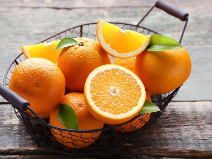 Close-up of a woman tasting sour lemon and smiling.