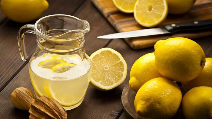 asam Close-up of a woman tasting sour lemon and smiling.