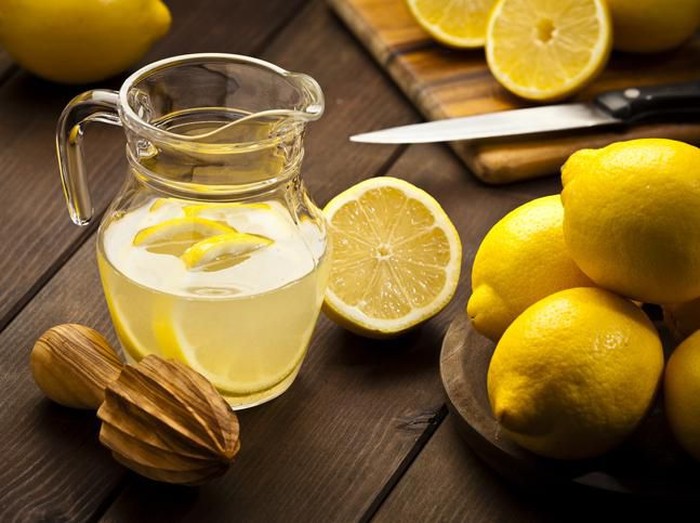 Close-up of a woman tasting sour lemon and smiling.