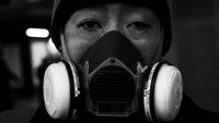 Sejumlah warga dengan topeng gas mencul dari seluruh sudut kota. Mereka diliput ketakutan akan penyebaran virus corona.