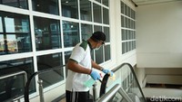 AP I Bandara I Gusti Ngurah Rai melakukan pembersihan dengan disinfektan di fasilitas terminal penumpang. Seorang petugas membersihkan pegangan eskalator (Foto: Angga Riza/detikcom)
