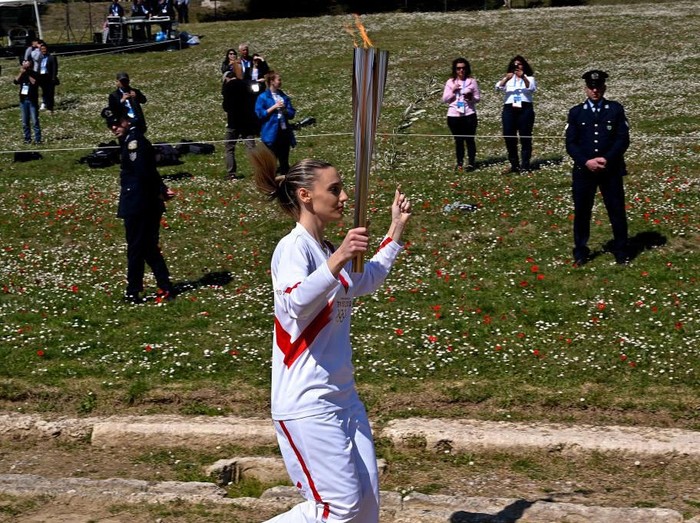 ATHENS, GREECE - MARCH 12:  Torchbearer Greeces Anna Korakaki, Rio 2016 gold medallist in the 25m pistol shooting,  past empty stadium as she holds the Olympic flame and an olive branch during the flame lighting ceremony on March 12, 2020 in ancient Olympia, ahead of the Tokyo 2020 Olympic Games . (Photo by Milos Bicanski/Getty Images)