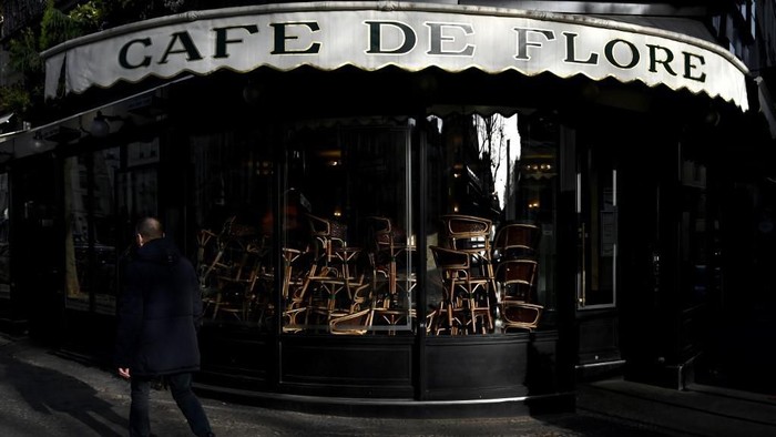 A picture taken on March 15, 2020 in Paris Saint-Germain-des-Pres district shows chairs piled up inside the Cafe de Flore as cafes and restaurants are closed amid spread of novel coronavirus (COVID-19). - France on March 14, 2020 drastically stepped up its measures against the spread of the coronavirus, announcing the closure of all non-essential public places including restaurants and cafes. (Photo by Philippe LOPEZ / AFP)