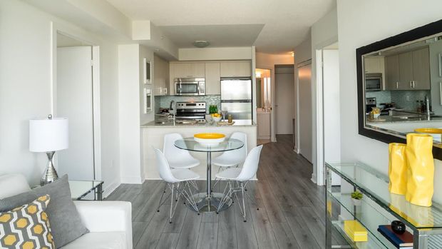 Living area/kitchen  interior of small rental condo property in uptown Toronto. Features large windows and open concept living/kitchen space with view of the bedroom.
