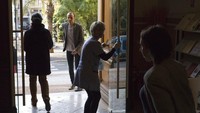 Seorang petugas menyemprotkan disinfektan ke seluruh permukaan pintu yang berada di lokasi pemungutan suara di kawasan Menton, Prancis Selatan, Minggu (15/3/2020). AP Photo/Daniel Cole.
