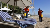 Seorang petugas menyemprotkan disinfektan di salah satu pantai yang berada di kawasan Bali, Minggu (15/3/2020).