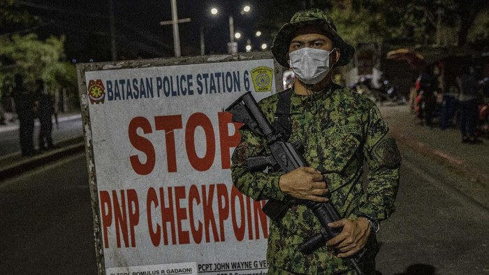 QUEZON, PHILIPPINES - MARCH 15: A police officer checks the temperature of a motorist at a checkpoint as authorities begin implementing a lockdown on Manila on March 15, 2020 in the outskirts of Metro Manila, Philippines. The Philippine government is placing some 12 million people in the capital Manila on lockdown as well as suspending government work for a month to prevent the spread of COVID-19. As of Saturday evening, the Philippines Department of Health has confirmed 111 cases of the deadly coronavirus in the country, with at least 8 recorded fatalities. (Photo by Ezra Acayan/Getty Images)