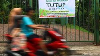 Warga melintas di depan pintu gerbang Taman Spathodea, Kebagusan.