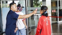 Petugas keamanan melakukan pengecekan suhu tubuh pengunjung Grand Pramuka Square Mall.
