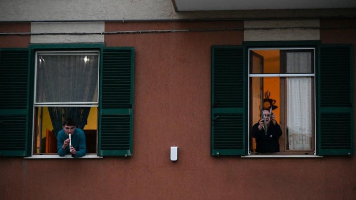 People play the Italian national anthem with music instruments and pot lids from the window of their house during a music flash mob called 