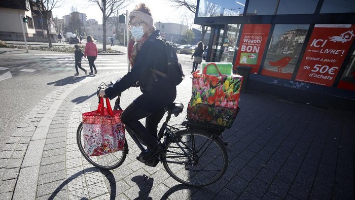 A woman rides her bicycle after shopping Monday March 16, 2020 in Strasbourg, eastern France. For most people, the new coronavirus causes only mild or moderate symptoms. For some it can cause more severe illness. (AP Photo/Jean-Francois Badias)