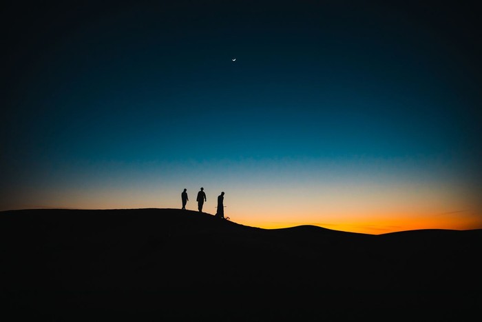 Arabs, Middle East, Culture - Three Arab men walking behind each other on the sand dunes