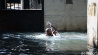 Genangan air yang cukup tinggi itu dimanfaatkan seorang anak untuk berenang dan bermain air.