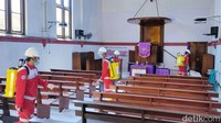 Petugas menyisir area gereja untuk disinfeksi corona.