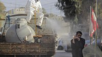 Seorang petugas menyemprot cairan disinfektan dari atas truk (AP/Aaron Favila)