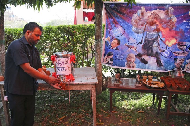 Karikatur virus corona terpampang di acara tersebut. Apakah air kencing seni benar-benar ampuh menangkal virus corona? Menurut Reuters, belum ada bukti medis yang mendukung klaim mereka. (Foto: AP/Altaf Qadri)