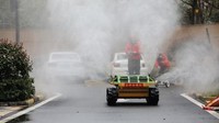 Sebuah mobil robot yang dikendalikan menggunakan remote control menyemprotkan cairan disinfektan di jalanan (AP/Aaron Favila)