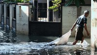 Seorang warga tampak beraktivitas seperti biasa meski genangan air merendam kawasan permukiman Jakarta Timur imbas hujan deras yang mengguyur wilayah Jakarta pada Senin (16/3) kemarin.