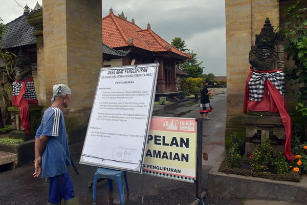 Warga membaca pengumuman yang mengenai informasi penutupan sementara pariwisata di Desa Wisata Penglipuran, Bangli, Bali, Rabu (18/3/2020). Foto: ANTARA FOTO/Nyoman Hendra Wibowo Warga membaca pengumuman yang mengenai informasi penutupan sementara pariwisata di Desa Wisata Penglipuran, Bangli, Bali, Rabu (18/3/2020). Foto: ANTARA FOTO/Nyoman Hendra Wibowo